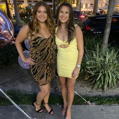 two women standing next to each other on a sidewalk