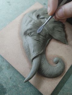 someone is carving an elephant head out of clay