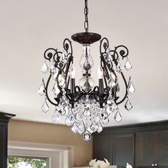 a chandelier hanging from the ceiling in a kitchen with dark wood cabinets and white flowers