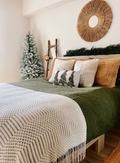 a bedroom decorated for christmas with green bedding and white blankets, pine tree on the headboard