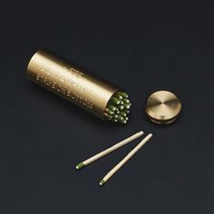 three green and white toothbrushes sitting next to a gold container with matches on it