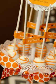 orange and white cake pops with name tags on them