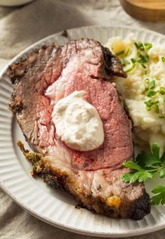 a plate with meat, mashed potatoes and garnish on it next to a fork