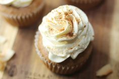 cupcakes with white frosting and cinnamon sprinkles on a wooden surface