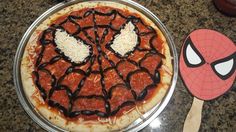 a spiderman pizza with cheese and sauce on it