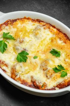 a casserole dish with cheese and parsley garnished in sauce on a table