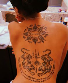 the back of a woman's body with tattoos on it