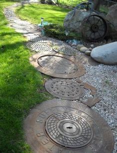 an iron manhole cover in the middle of a yard with grass and rocks around it