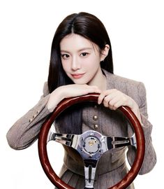 a woman holding the steering wheel of a car while wearing a suit and jacket with her hands on the steering wheel