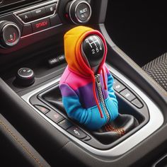 a colorful hoodie sitting on the center console of a car, with buttons and controls