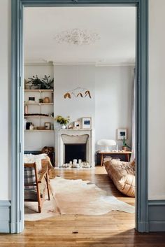 an open door leading to a living room with furniture and decor on the floor, in front of a fireplace