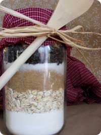 a jar filled with oatmeal, raisins and other things next to a wooden spoon