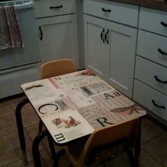 a table and chairs in a kitchen with newspaper on the table, next to an oven