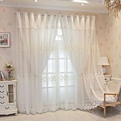 a living room with white curtains and floral wallpaper