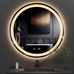 a bathroom with a round mirror above the sink and a black tub in front of it