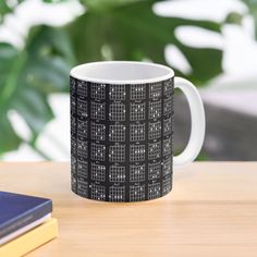 a black and white coffee mug sitting on top of a table next to a book