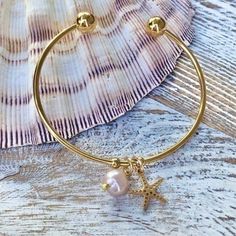 Add A Dainty Touch To Your Everyday Look With This Beautiful Freshwater Pearl Charmed Bangle! Featuring An Adjustable Stainless Steel Gold Cuff Bangle Designed With 1 Freshwater Pearl Charm That Is A Pink Champagne Color, 1 Gold Starfish Charm That Is Stainless Steel And Also 2 Stopper Beads To Keep Charms In Place. Perfect For Any Occasion Also Makes A Lovely Gift. Gold Cuffs, Bangle Designs, Bangle Bracelets With Charms, Pink Champagne, Champagne Color, Charm Bangle, Pearl Charms, Handmade Gold, Beach Jewelry