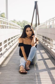 a woman is sitting on a bridge and posing for the camera