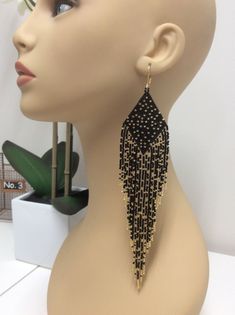 a mannequin head with a pair of black and gold beaded earrings on it