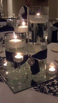 candles are placed in glass vases on a table