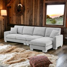 a living room with wood paneling and a large sectional couch in front of a window