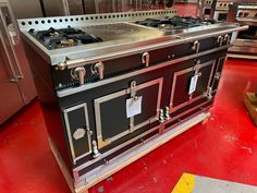 an old fashioned stove is on display in a kitchen setting with red flooring and stainless steel appliances