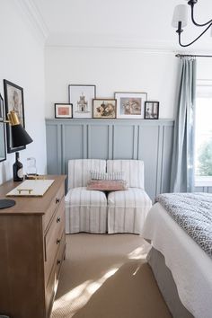 a bed room with a neatly made bed next to a dresser and a chair in front of a window