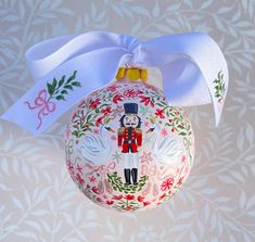 a decorated christmas ornament with a white ribbon on it's head and an image of a nutcracker