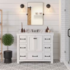 a bathroom with white cabinets and marble counter tops, along with a potted plant