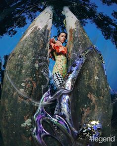 a woman standing on top of a large rock next to a giant tree trunk with an octopus in it's mouth