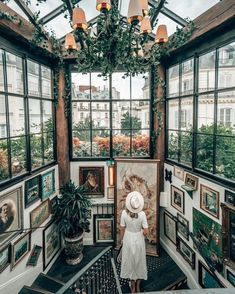 a woman in a white dress and hat is walking up the stairs to an art gallery