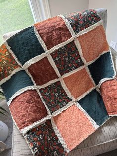 a couch with a quilt on top of it next to a potted plant in front of a window