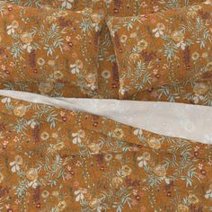 an orange floral print bed spread with two pillow cases and one is folded up to the side