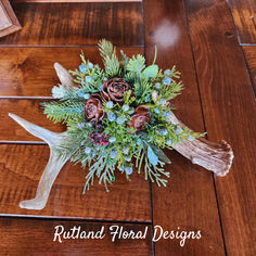 a bouquet made out of deer antlers and greenery on a wooden floor with the words rattand floral designs