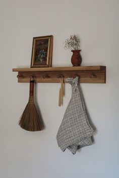 a wall shelf with two brooms and a potted plant hanging on it's side