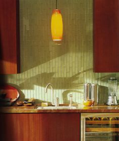 a yellow light hanging over a kitchen counter next to a stove top oven and microwave