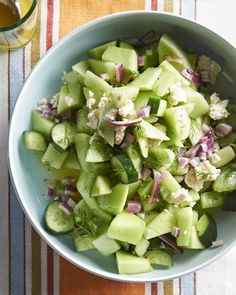 a bowl filled with cucumber and onions on top of a striped table cloth