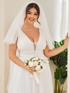 a woman in a white wedding dress holding a bouquet and posing for the camera with her hands on her hips