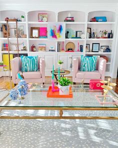 a living room with two couches and a coffee table in front of a bookshelf