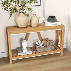 a wooden table with two vases and books on it next to a planter