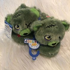 two green stuffed animals sitting next to each other on a white fur covered surface,