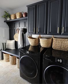 a black washer and dryer in a room with baskets on the back wall