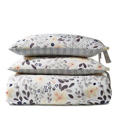 three pillows stacked on top of each other in front of a white background with flowers