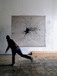 a man is running in an empty room with a large piece of artwork behind him