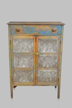 an old wooden cabinet with glass doors and metal knobs on the front, against a gray background