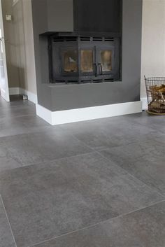 a living room with grey tile floors and a fireplace in the corner, next to a wicker basket