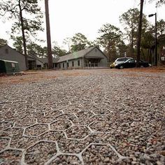 a car parked in front of a house next to some trees and rocks on the ground