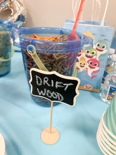 a blue table topped with plastic cups filled with food next to paper plates and napkins