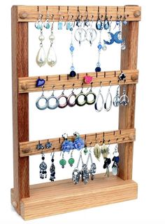 a wooden jewelry rack with several pairs of earrings hanging from it's sides,