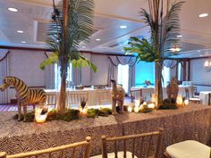 a table with zebras, candles and palm trees on it in a large room